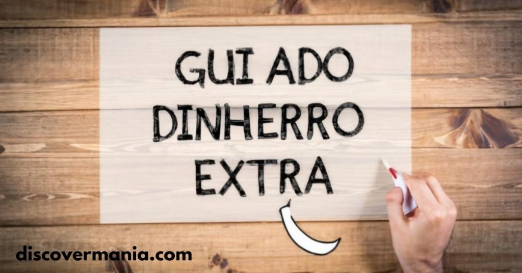 A hand with a red marker is writing "Guiadodinheiroextra" on a wooden background with large black text, resembling a chalkboard or sign. The website "discovermania.com" is displayed at the bottom.